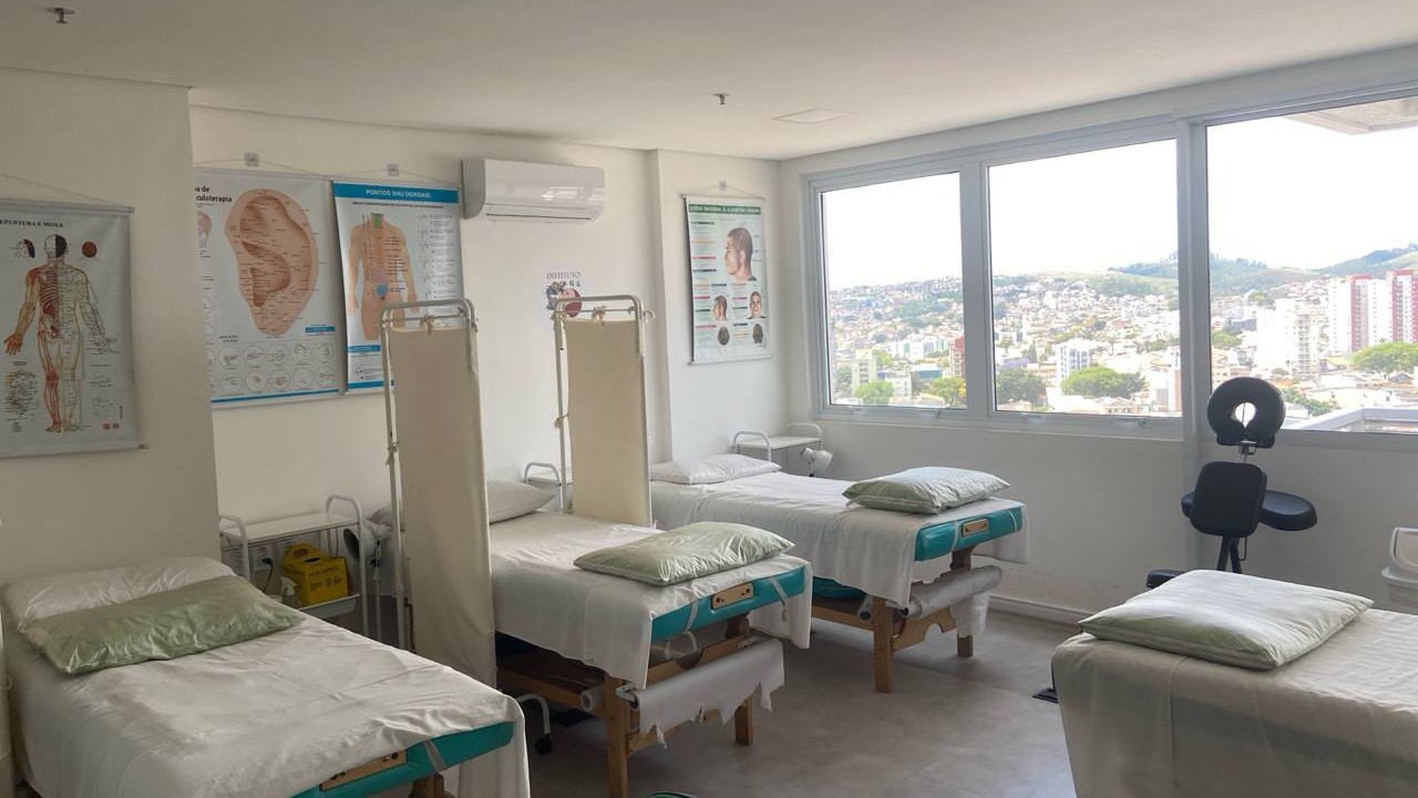 Ambulatório clínico do Instituto Long Tao com macas, mapas de acupuntura e vista da cidade